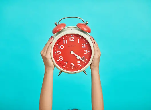 Hands holding clock on bright background